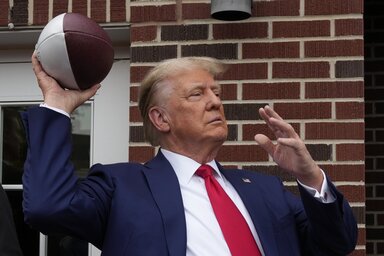 Former President Donald Trump prepares to throw a football to the crowd during a visit to the Alpha Gamma Rho, agricultural fraternity, at Iowa State University before an NCAA college footba
