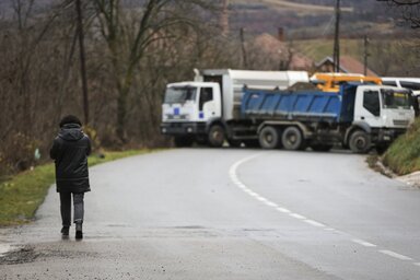 A woman walks towards a road blocked with heavy vehicles in the village of Rudare, northern Kosovo on Sunday, Dec. 11, 2022. Tensions were high in northern Kosovo on Sunday, with Serbs block