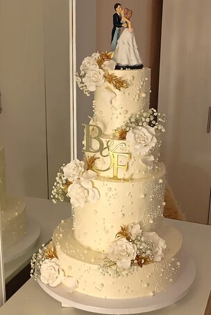 Letisztult elegancia és romantika egyetlen tortában – ez a fehér-arany esküvői torta gyöngyökkel, rózsákkal és egy szerelmes pár sziluettjével méltó dísze a nagy napnak (Fotó: Huszta Henrietta archívuma)