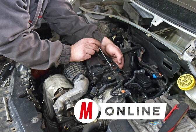 Az autószerelő műhelyben két szerelő javítja a járműveket