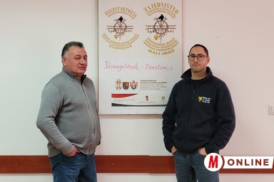 Szűgyi István és Kurin Ákos a tűzoltóverseny és -találkozó plakátja előtt / Lakatos János felvétele