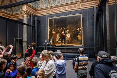 Rembrandt van Rijn Éjjeli őrjárat című festménye az amszterdami Rijksmuseumban, az alkotás restaurálását egy üvegfal mögött végzik (Torval Mork / Shutterstock)