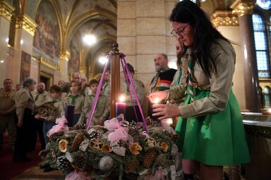 A betlehemi békelánggal meggyújtja egy cserkész a gyertyákat a parlamenti adventi koszorún az Országház Delegációs terme előtt (Fotó: MTI)