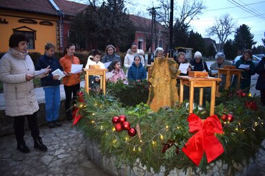 -	Énektanulás Nyúl Viktória vezetésével az adventi koszorúnál (Pacséri Művelődési Egyesület felvétele)