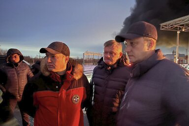 Roman Buszargin regionális kormányzó (jobbra) a Volga folyó túloldalán fekvő helyszínre látogatott a dróncsapás után. A háttérben látszó fekete füstoszlop feltehetően az olajraktárból száll