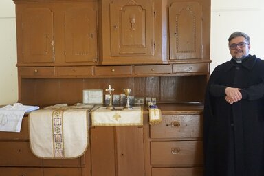 Szakály József topolyai plébános a múzeumnak ajándékozott sekrestyeszekrény előtt (Fotó: Topolya Község Múzeuma)