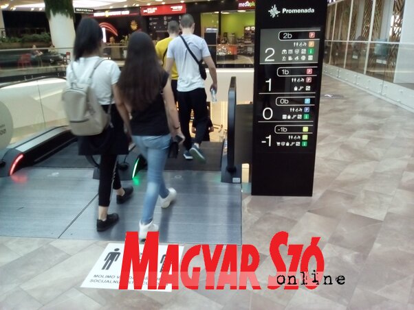 A Promenada bevásárlóközpontban minden megtesznek annak érdekében, hogy meggátolják a koronavírus terjedését. A pláza beltere egyébként is különösen tágas, hatalmas mennyiségű levegő van benn. A mozgólépcsők elé a két méteres távolságtartásra figyelmeztető matricákat ragasztottak. Valóban mindegyik alkalmazott, biztonsági őr és pincér szájmaszkot visel, a látogatok körében viszont csak elvétve látunk maszkot. A pláza vezetősége tehát mindent megtett a biztonság érdekében, a többi már tőlünk függ (Szeli Balázs felvétele)