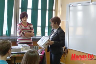 Nemes Ildikó magyartanár átveszi a diákkönyvtár számára Petkovics Mártától a könyvcsomagot. Háttérben a már felszerelt „okos tábla” (Góbor Béla felvétele)