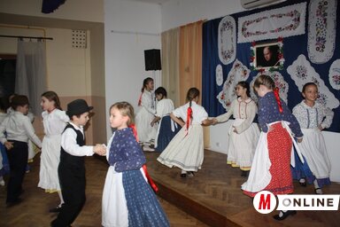 A bajsai Napsugár gyermek néptáncegyüttes, a háttérben a Fürge Ujjak kézimunkacsoport munkái (Kazinczy Paszterkó Diana felvétele)