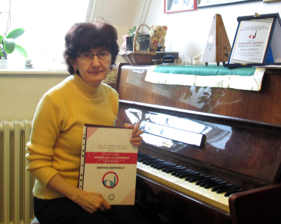 A tanárnő a díjai és a zongorája mellett