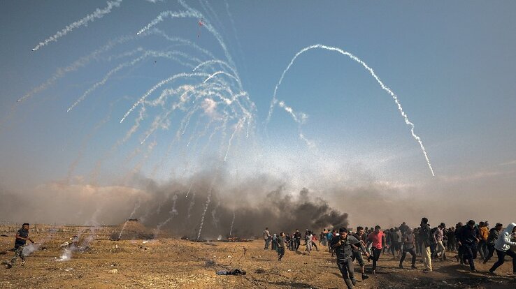 Palesztin tüntetők menekülnek fedezékbe az izraeli katonák által ellenük bevetett könnygázgránátok elől az izraeli-gázai határon, Fotó: MTI/EPA/Mohammed Szaber