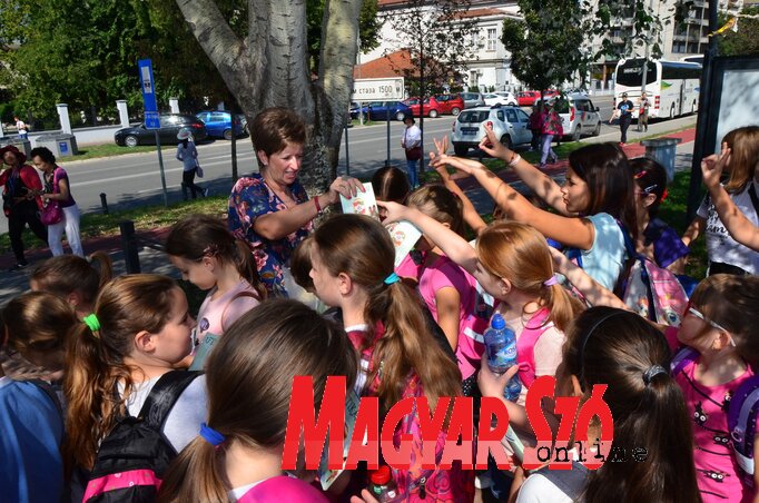 Jerasz Anikó kiosztja a kiránduló pajtásoknak az Útikalauz kiadványt