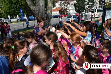 Jerasz Anikó kiosztja a kiránduló pajtásoknak az Útikalauz kiadványt