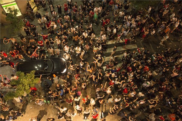 Egy autó próbál tovább haladni az úttesten vonuló, ünneplő tömeg között a Deák téren (Fotó: Kallos Bea/MTI)