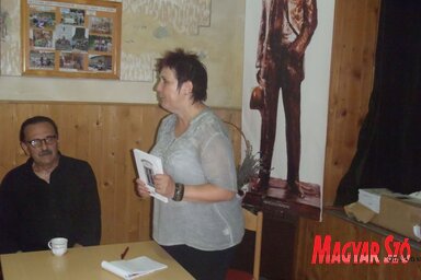 Tóth Lívia a megjelent riportkönyvvel a kezében, az asztalánál Léphaft Pál ül