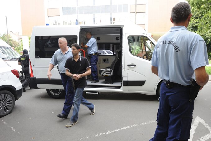 Rendőrök vezetik a per egyik vádlottját (Fotó: MTI)