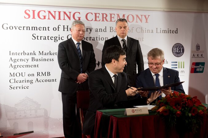 Matolcsy György, az MNB elnöke és Tien Kuo-li, a Bank of China elnöke stratégiai együttműködési szerződést ír alá a kínai bank budapesti székházában. Mögöttük Orbán Viktor miniszterelnök és Csielung Tuan, Kína budapesti nagykövete (Fotó: MTI)