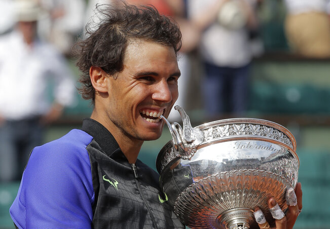 Spain's Rafael Nadal bites the trophy after defeating Switzerland's Stan Wawrinka in their final match of the French Open tennis tournament at the Roland Garros stadium, Sunday, June 11, 2017 in Paris. Nadal has won his record 10th French Open title, beat