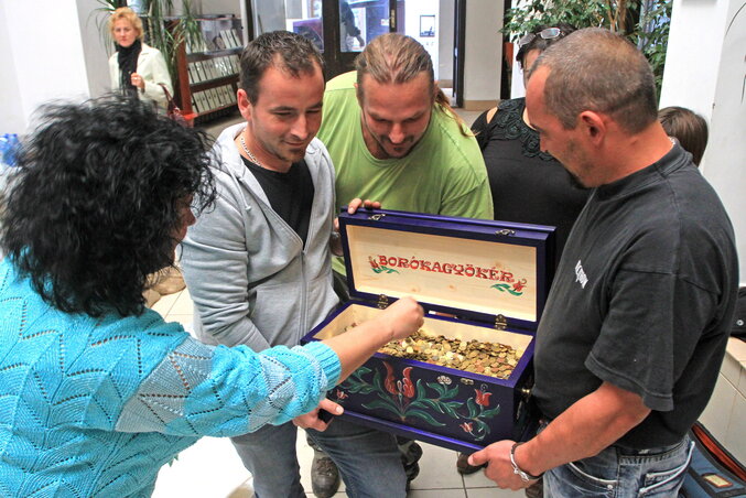 Önkéntesek átadnak egy doboz aprópénzt Lakó Péterfi Tündének (Fotó: MTI)