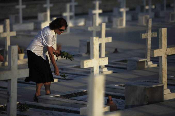 Egy asszony virágot helyez a 1974-es török invázió idején elesett katona sírjára a kettéosztott Nicosia katonai temetőjében (Fotó: Beta/AP)
