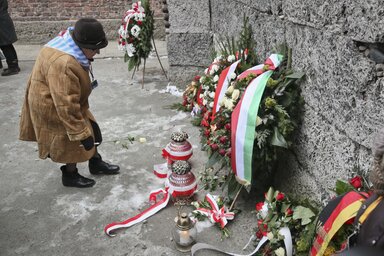 Holokauszttúlélő helyez el egy rózsaszálat a „halál fala” előtt (Fotó: Beta/AP)