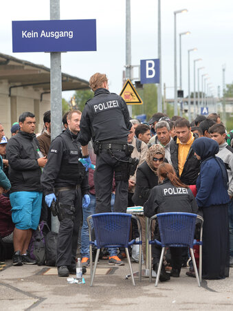 Német rendőrök menekülteket regisztrálnak a freilassingi vasútállomáson, mielőtt autóbuszokkal továbbszállítanák őket (Fotó: Beta/AP)