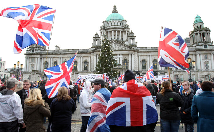 Brit lobogókat lengető protestánsok csoportjai tüntetnek a belfasti városháza előtt, amiatt, hogy a – katolikus többségű – városi parlament a városházáról levetette a brit zászlót Brit lobogókat lengető protestánsok csoportjai tüntetnek a belfasti városháza előtt, amiatt, hogy a – katolikus többségű – városi parlament a városházáról levetette a brit zászlót