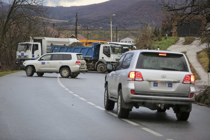 EU Rule of Law (EULEX) members reverse their vehicles at the road blocked with heavy vehicles in the village of Rudare, northern Kosovo on Sunday, Dec. 11, 2022. Tensions were high in northe
