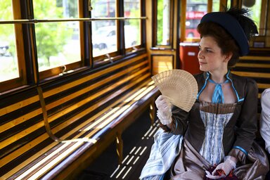 A 19. századot megidéző, korabeli ruhákba öltözött hölgy a Magyar Nemzeti Múzeum nosztalgiavillamosán (MTI/ Hegedűs Róbert)