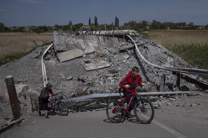 Biciklizés az Orihiv közelében lerombolt hídnál (Fotó: AP/Beta)