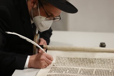 Shaul Nekrich rabbi a Reichstagban tartott megemlékezésen az 1792-ből származó Sulzbachi Tórát egészíti ki. A 2013-ban előkerült és felújított tóratekercs utolsó betűit jelképesen most írta be (Fotó: Beta/AP)