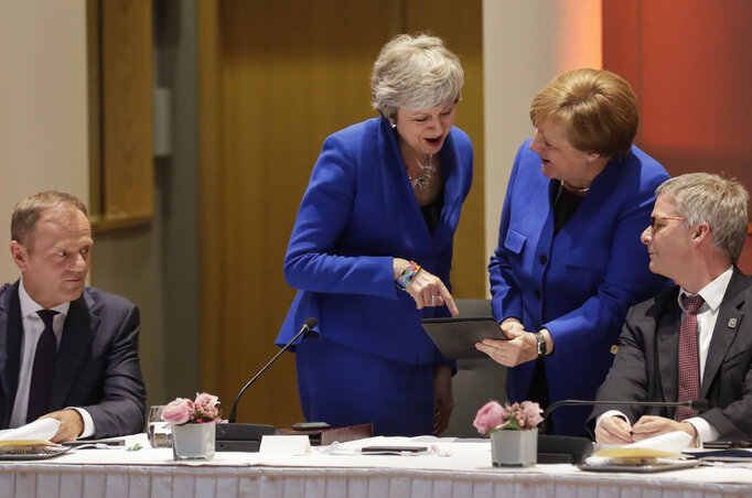 Az éjszakába nyúló tárgyalások után May és Merkel egy táblagépen mutogat egymásnak valamit (AP/Beta) Az éjszakába nyúló tárgyalások után May és Merkel egy táblagépen mutogat egymásnak valamit (AP/Beta)