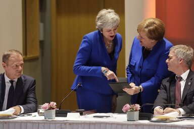 Az éjszakába nyúló tárgyalások után May és Merkel egy táblagépen mutogat egymásnak valamit (AP/Beta)