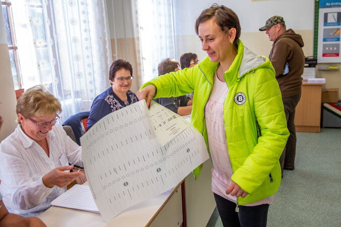 Zengő Zoltánné átveszi a szavazólapot a kunágotai általános iskolában kialakított szavazókörben 2019. október 13-án. A településen - ahol 49 egyéni listás jelölt indul - szavaznak az ország legnagyobb, 420x635 milliméteres szavazólapjával (Fotó: MTI)