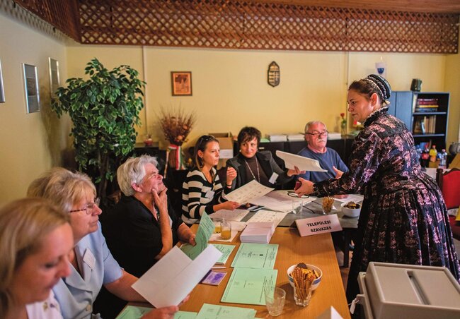 Az újpetrei hagyományos Duna menti német népviseletbe öltözött Erdeiné Csütörtök Teodóra átveszi a szavazólapját a Baranya megyei település önkormányzati hivatalában kialakított szavazókörben (Fotó:MTI)